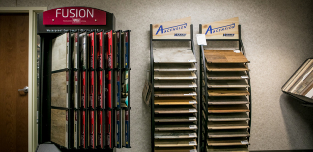 Display racks with various flooring samples labeled Fusion and Ascension