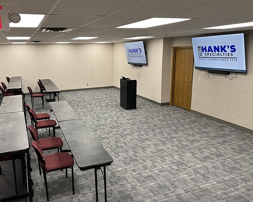 Training room with tables, red chairs, and Hank's Specialties screens