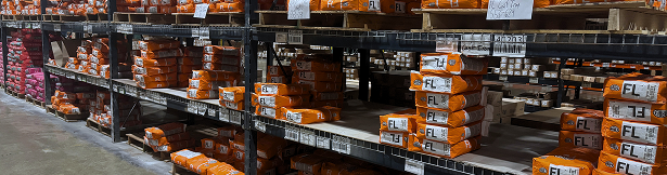 Warehouse shelves with stacked orange bags of floor leveler
