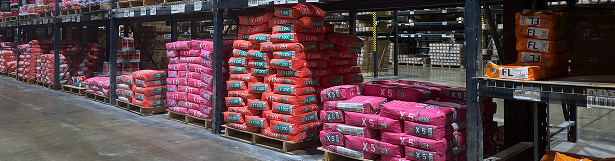 Pallets of pink and red construction bags stacked on warehouse shelves