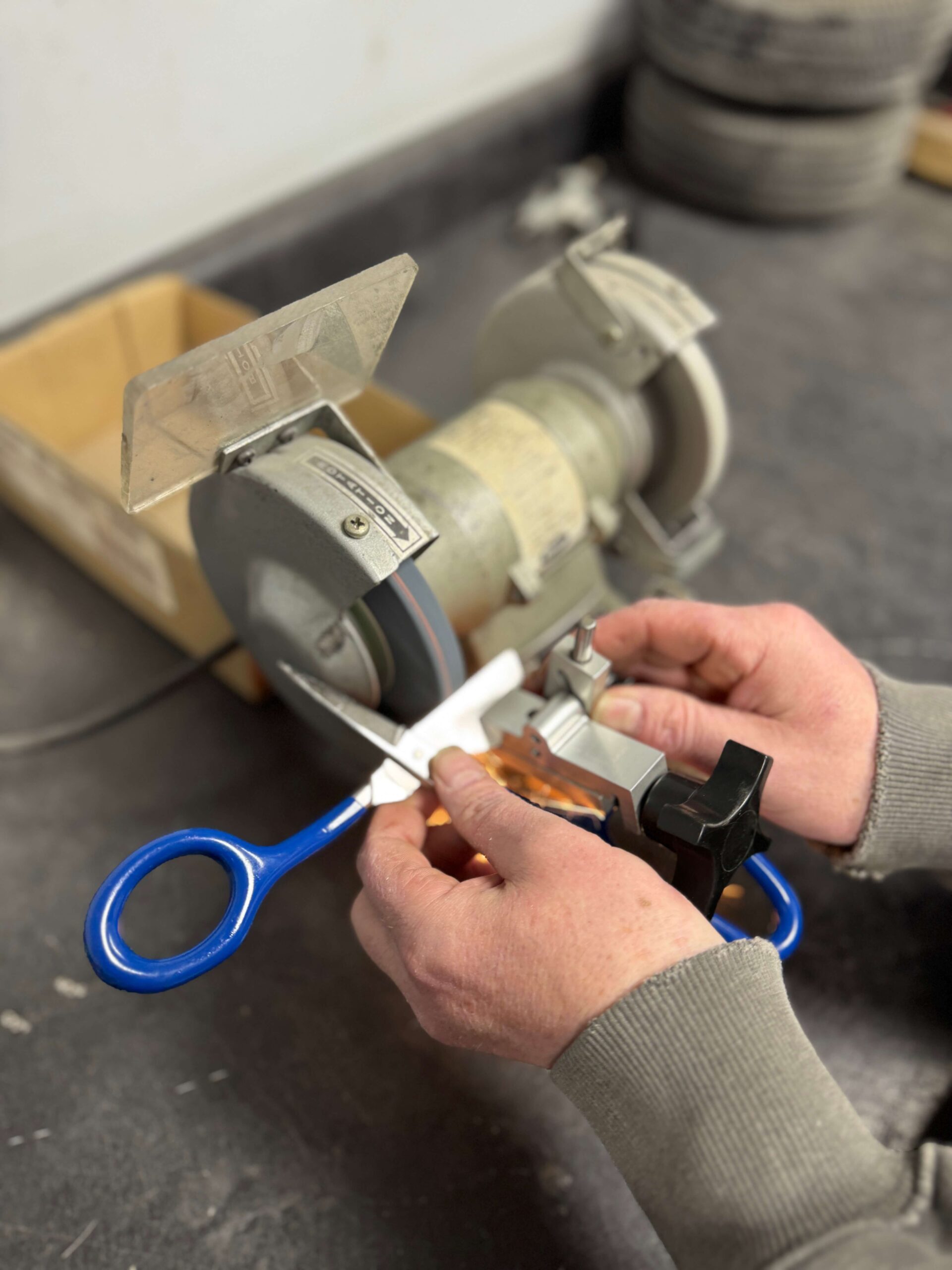 Person sharpening scissors using a bench grinder