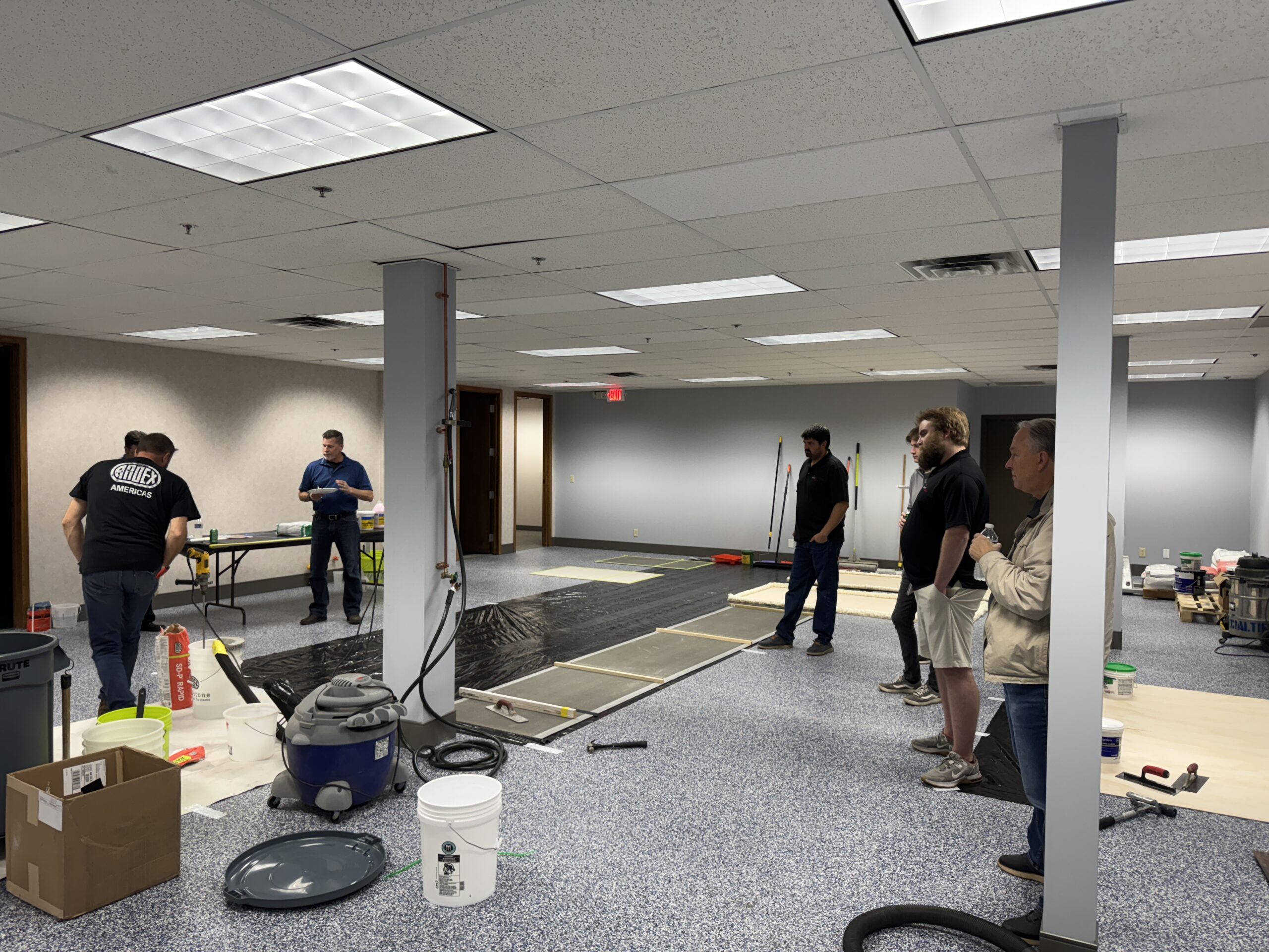 Group observing flooring installation demo in a renovated room