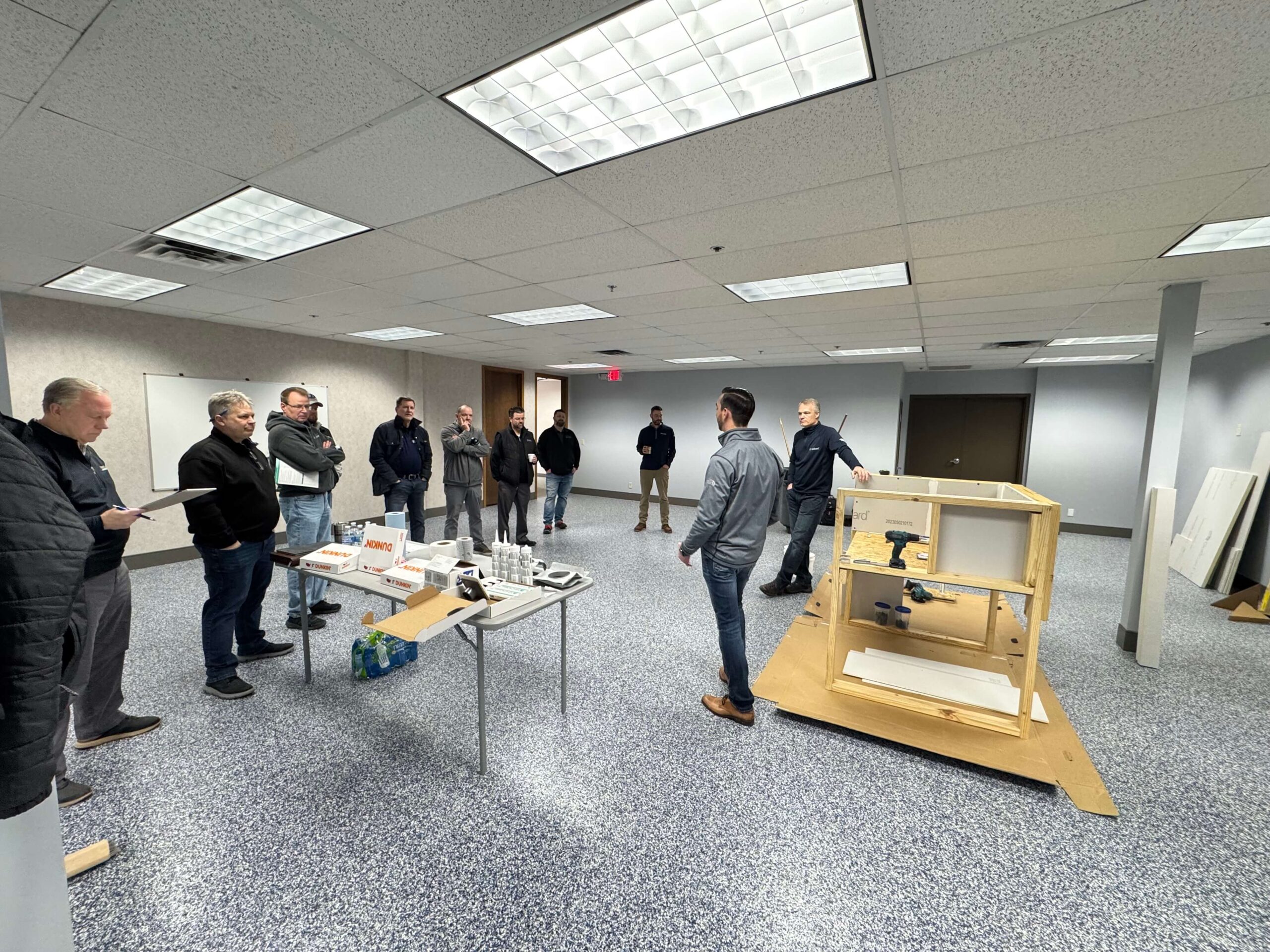 Group gathered for product demo with display table and wooden frame