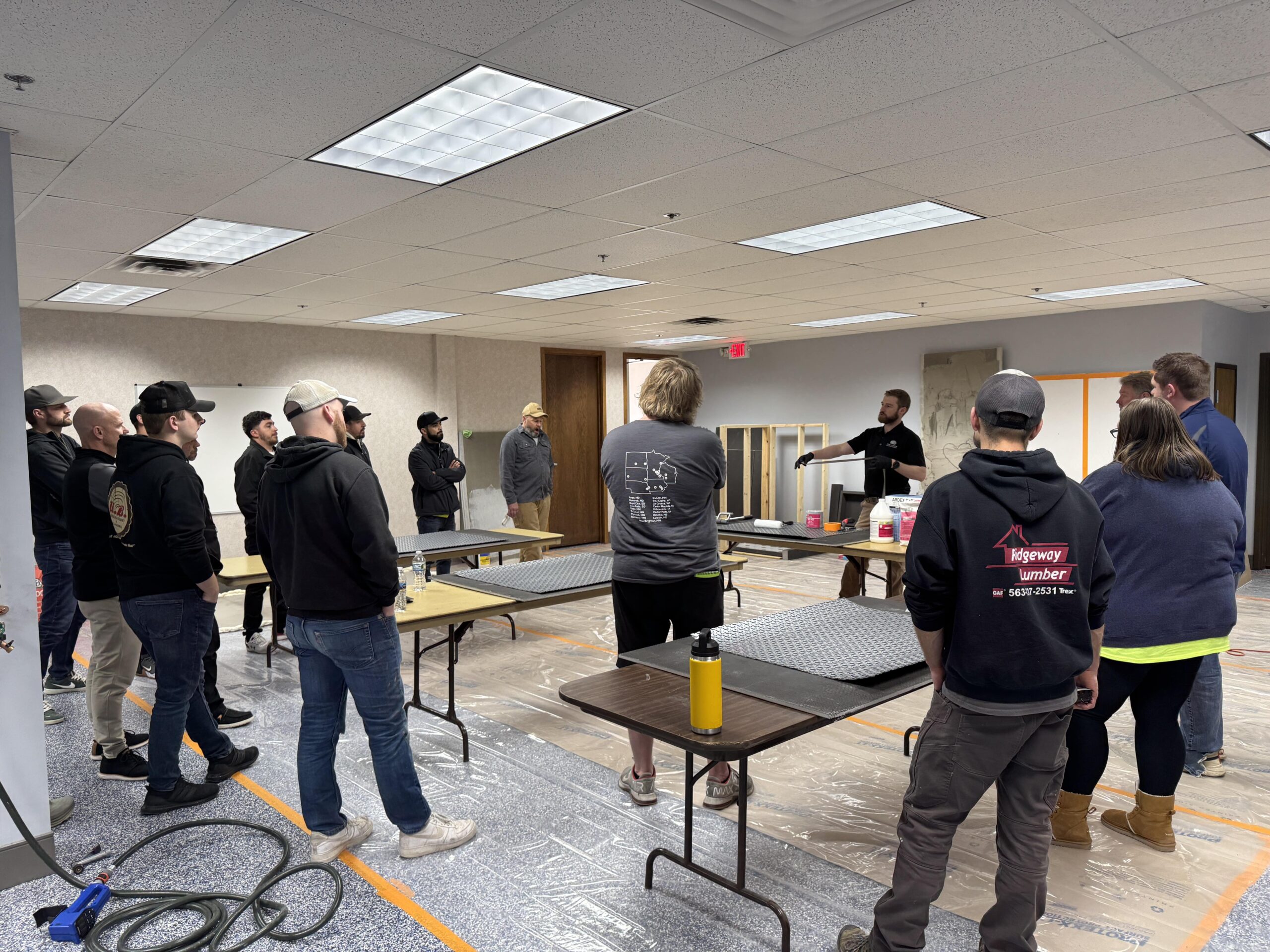 Instructor giving demo to group in room with tables and floor mats